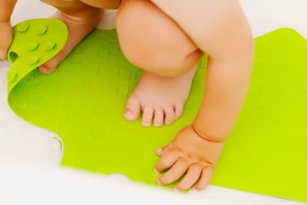 Baby playing with a green safety bath mat.